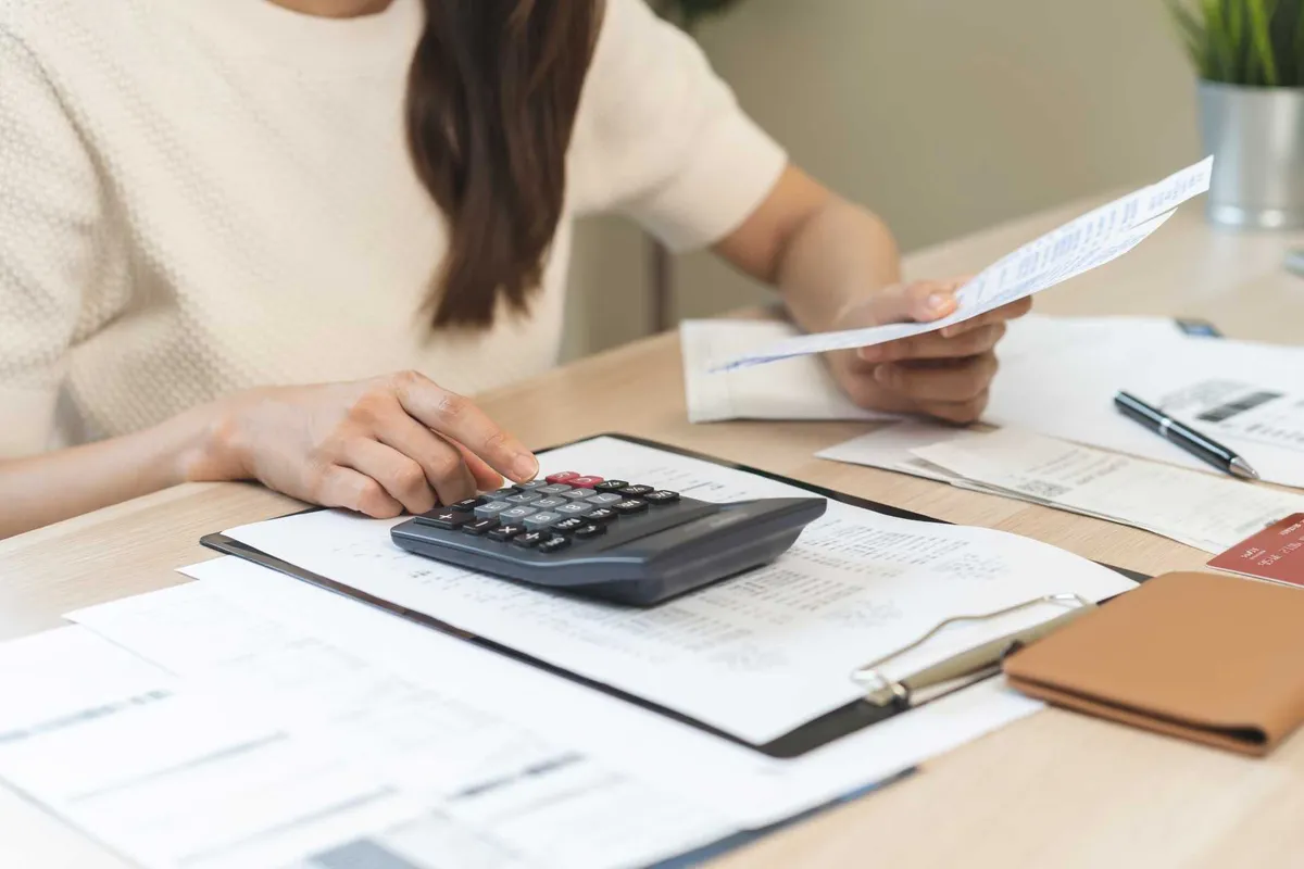 Persona calculando la base imponible de una factura con una calculadora