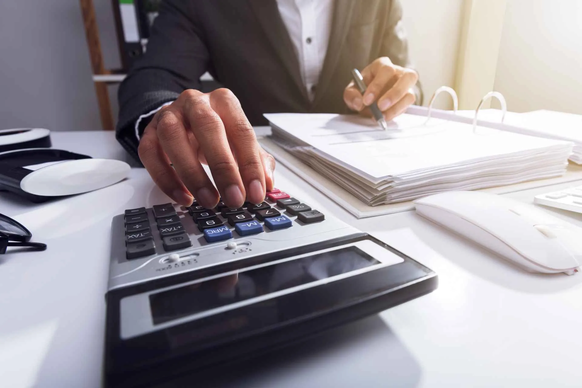 Contador usando una calculadora junto a una carpeta con documentación para liquidar sueldos